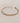 Gold bracelet with clear stones on a beige background