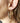 Gold hoop earring worn by a person with blurred background