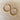 Two gold hoop earrings on a beige fabric background