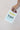 Hand holding a card with 'Congrats on making a tiny human' text against a plain background